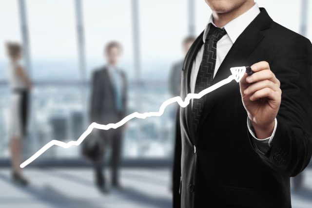 a man in a suit is drawing a line graph.